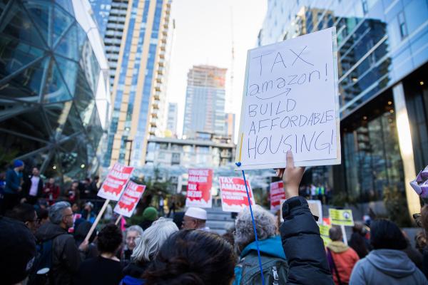 Dwarfed by the Amazon Spheres and additional buildings connected to the sprawling campus, protesters gather to rally for new taxes on large businesses in Seattle to pay for affordable housing. Photo by Alex Garland