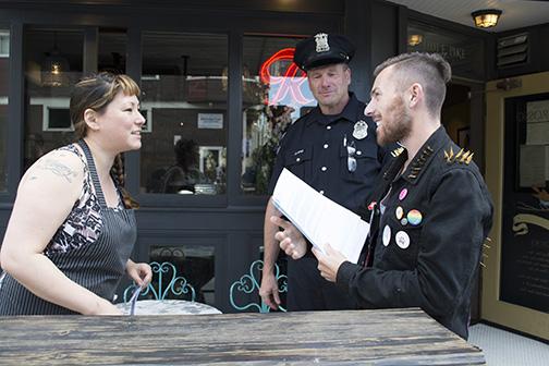 Doug Vitaly, right, of the Sisters of the Mother House of Washington, and Seattle Police Department LGBTQ liaison Officer Jim Ritter explain the safe place program to Miki Sodos, left, co-owner of the Capitol Hill restaurant Cafe Pettirosso. 