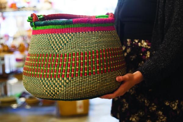 Woman holding a Gambibgo pot basket made in northern Ghana out of elephant grass. 