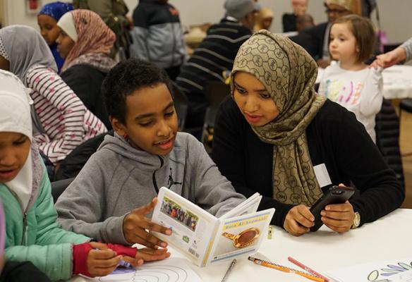 Families at New Holly Gathering Hall read “Baro Af-Soomaali,” a children’s book about Somali culture created by local families. Photo by Susan Fried