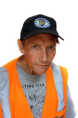 Middle-aged white man wearing black cap and orange vendor vest over gray T-shirt with words "Flying Fish"
