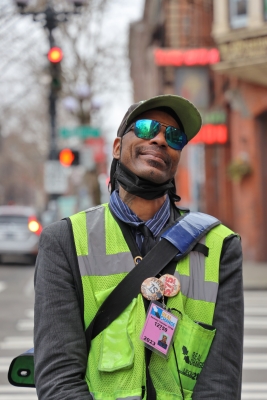 Vendor Zackary Tutwiler standing on the street in his yellow vest with a cap and shades on.