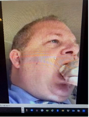 Photo, taken from below, of middle-aged white man with crewcut putting food in his mouth