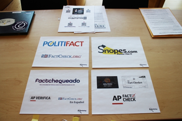 Four organizations--Politifact, Snopes.com, Factchequeado, and AP Fact Check--are represented by four sheets of paper laid side by side on table