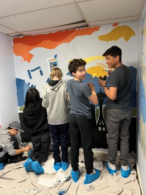A group of eighth graders work on a mural in the Real Change offices.