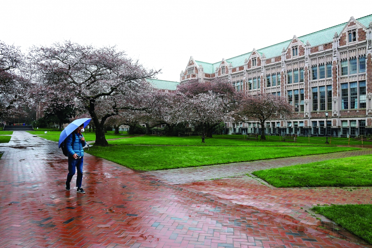 A student wearing a mask walks through an empty University of Washington Campus after classes were canceled.