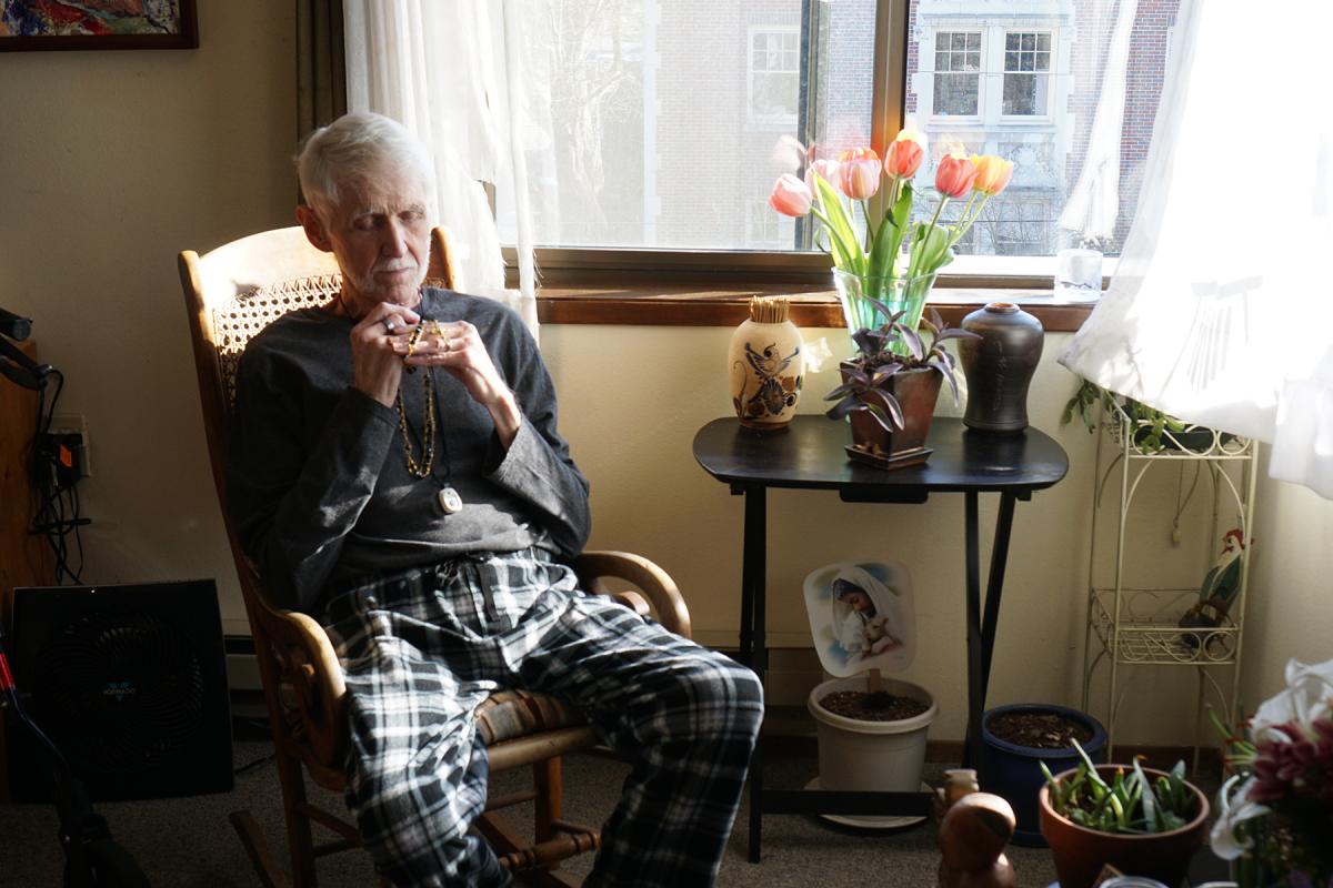 Robert Fuller sits in his apartment on Capitol Hill, contemplating his rosary. Photo by Wes Sauer