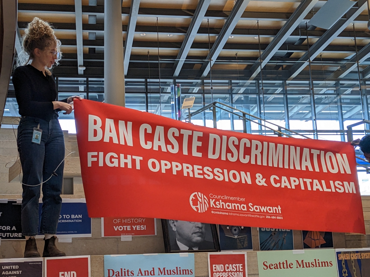 A supporter of the caste discrimination legislation holds a banner at a rally held inside Seattle City Hall.