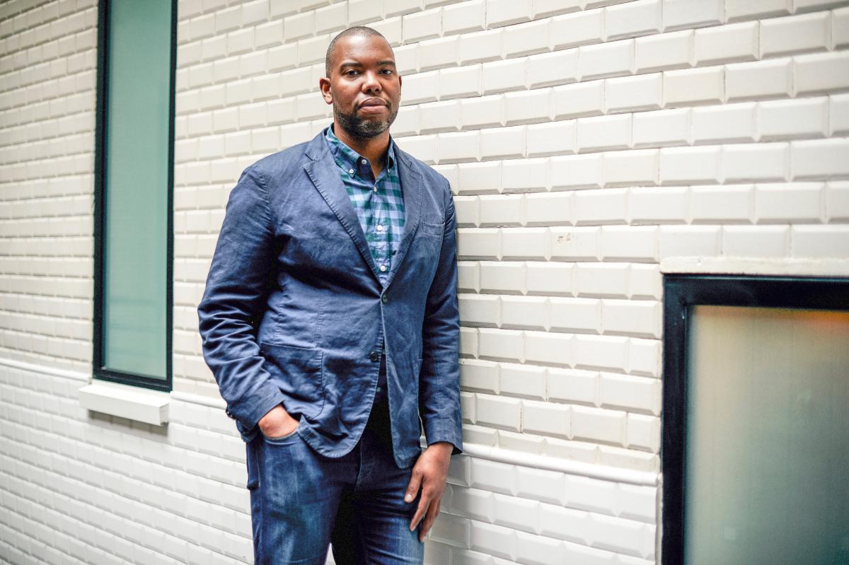 Journalist Ta-Nehisi Coates standing in a hallway, leaning against the wall.