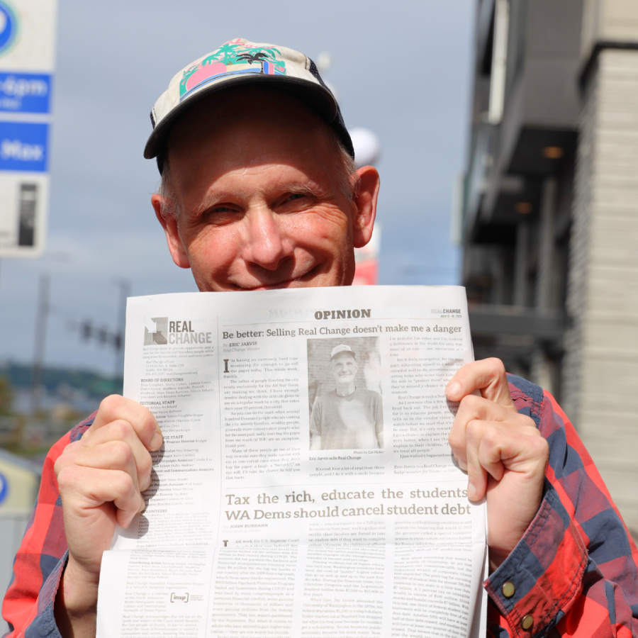 Eric Jarvis, a middle-aged white man in a cap, holds up a copy of the newspaper
