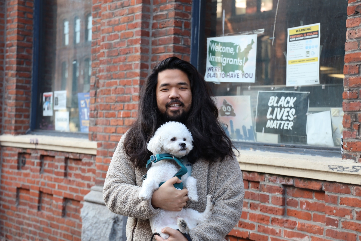 Dae Shik Kim Jr. holds his dog in front of the Real Change office