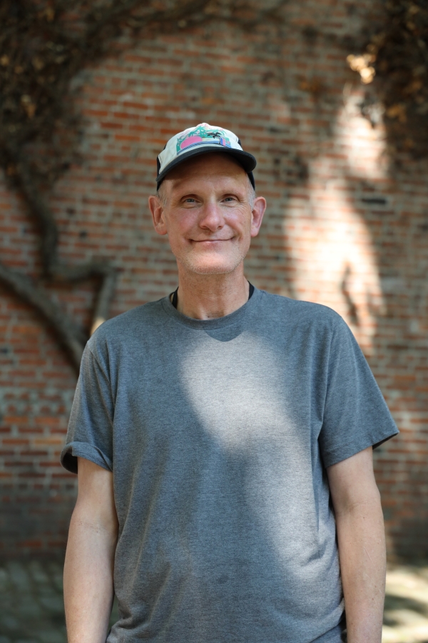 A portrait of a middle-aged white man wearing a baseball cap.