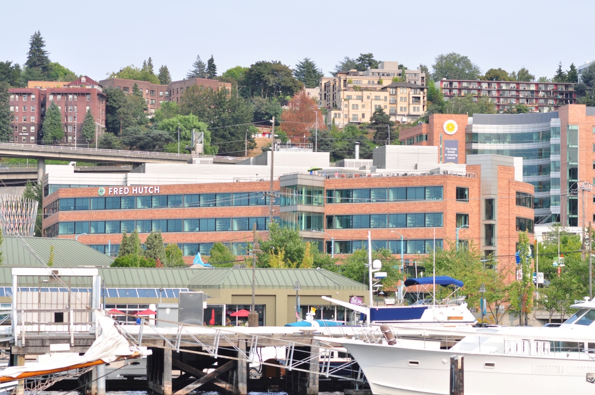Wide-angle view of red Fred Hutch building behind marina on sunny day