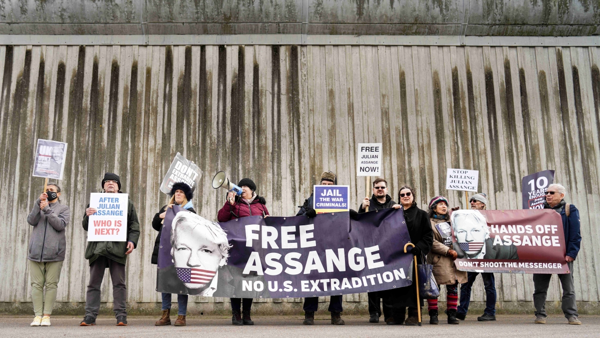 Photograph of people standing in a row holding signs calling for freedom for Julian Assange