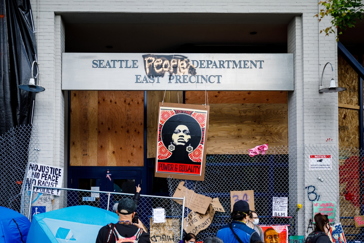 Photograph of Seattle Police Department's East Precinct entrance as it appeared in 2020, with fence barring entrance and a banner reading "People's" covering the word "Police" and 