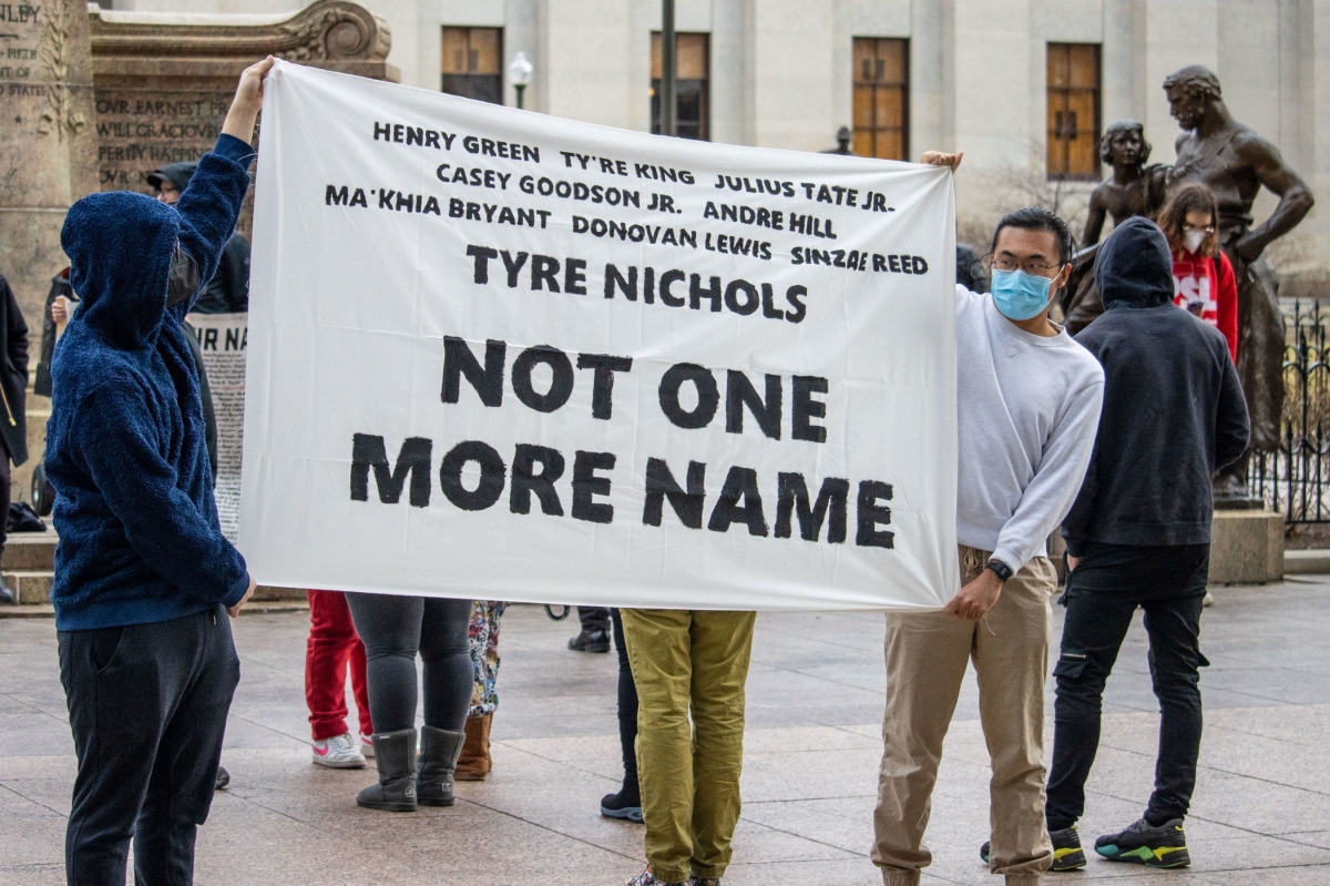 Young people hold up a banner memorializing Tyre Nichols, and other names listed, and the phrase, "Not One More Name"