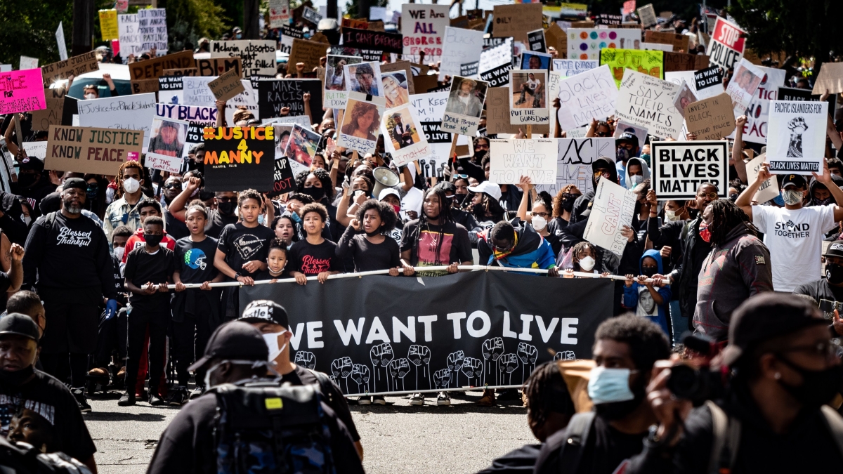 Protesters march holding signs in support of Black lives and victims of police violence