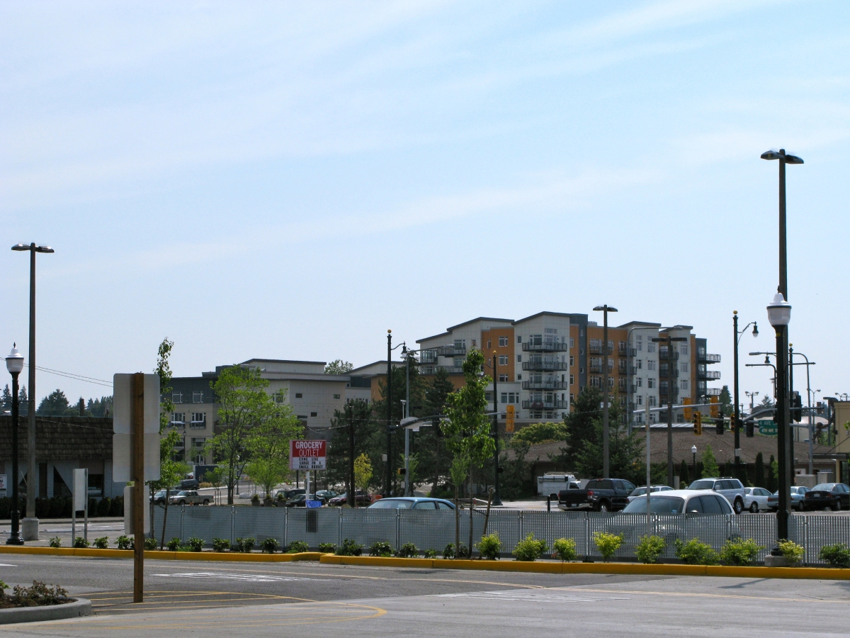 Panoramic photograph of row of buildings behind parked cars and a "Grocery Outlet" sign