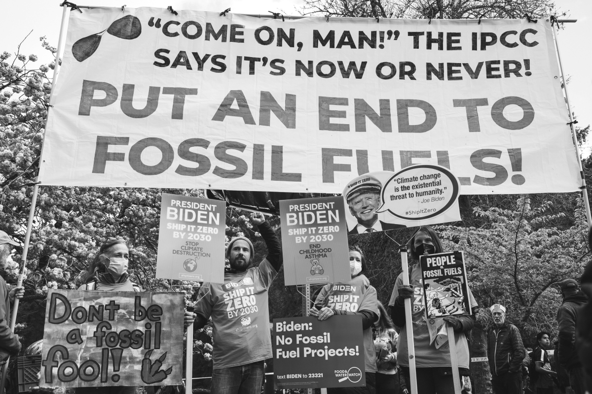 People stand in front of banner reading, "'Come on, man!' The IPCC says it's now or never! Put an end to fossil fuels!"