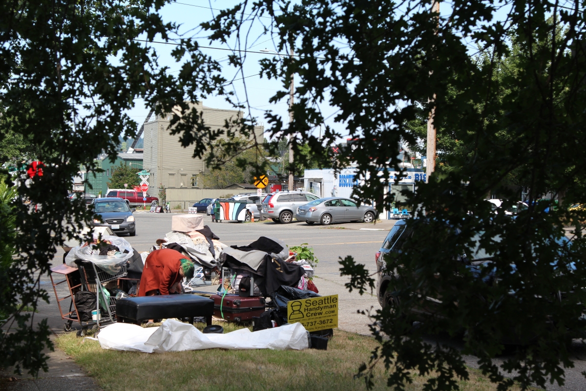 Angel sorts through a large pile of her belongings, sitting on a street corner along Leary Way NW in Frelard.