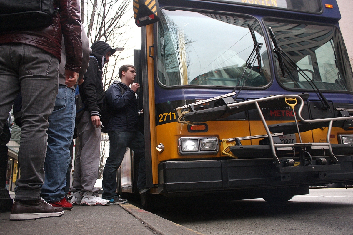 Photograph of men queuing up to board bus, seen from ground level
