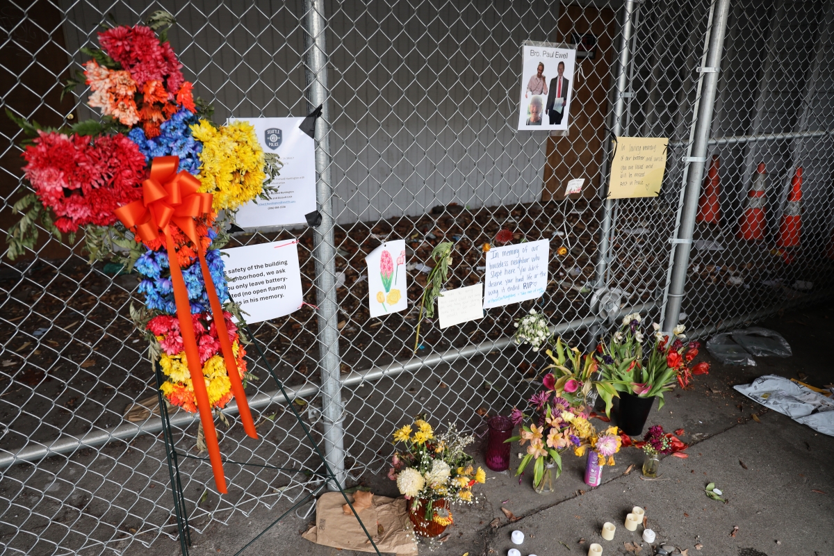 Flowers, signs and electronic candles decorate a chain link fence in memory of Paul Ewell.