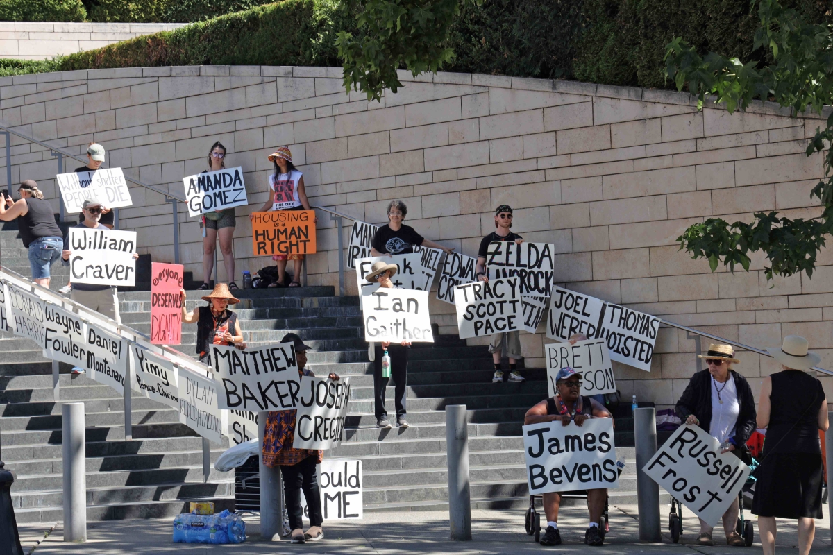 Photograph of people lining a flight of steps, holding signs displaying names