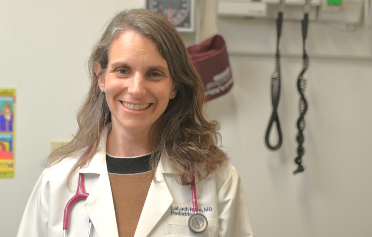 Image of middle-aged white woman with shoulder-length hair in doctor's coat and stethoscope