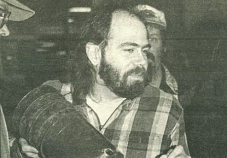 Cropped photo of homelessness activist Scott Morrow in a flannel shirt and holding a shovel from an April 1996 demonstration outside of Seattle City Hall