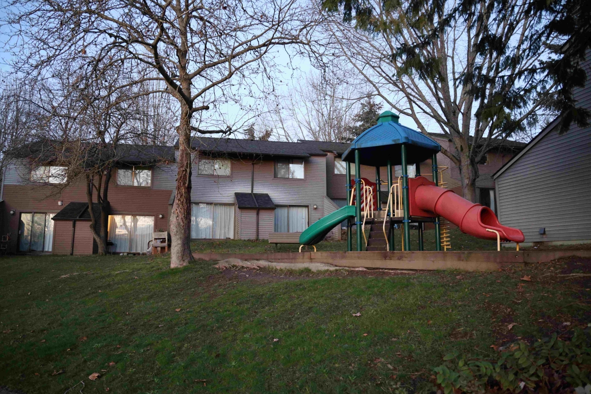 View of playground in front of two-story apartment housing on cloudy day