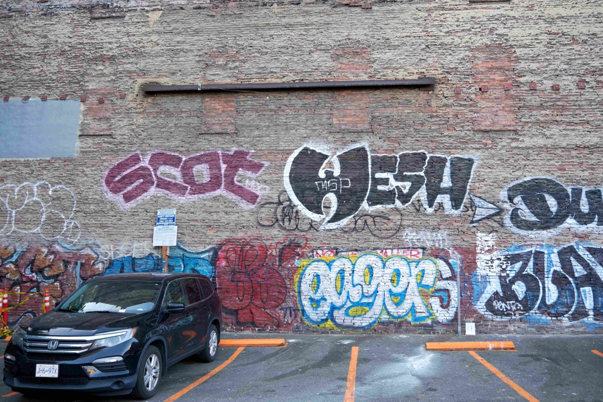 Photograph of brick wall of parking lot covered with graffiti