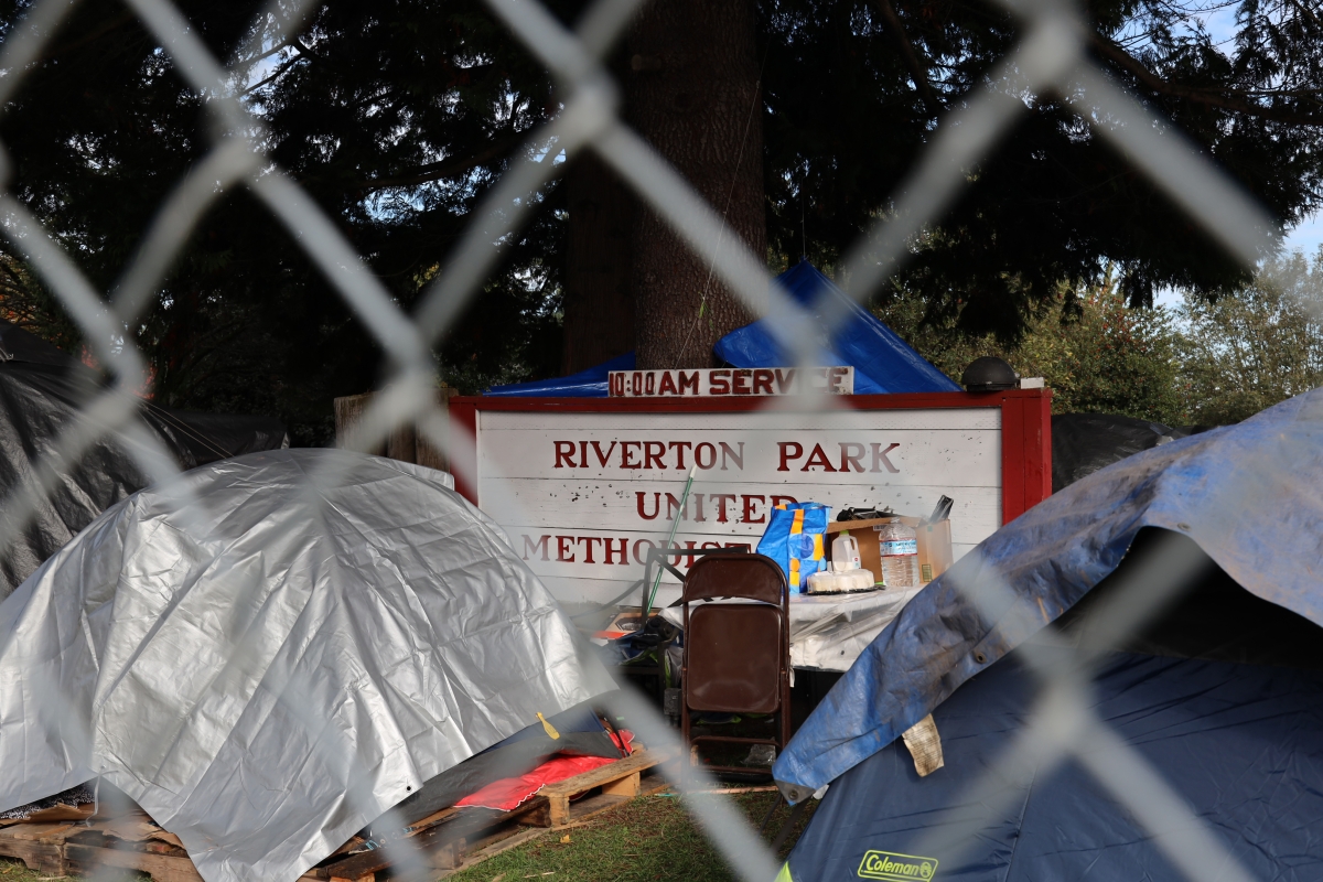 Tents and the church sign behind a chain link fence