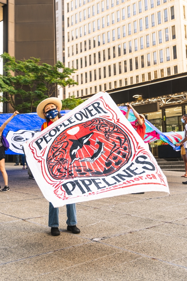 Activists hold banners outside of Liberty Mutual’s Vancouver, BC, Canada, headquarters in protest over the insurance company’s coverage of the Trans Mountain Pipeline, June 2021.