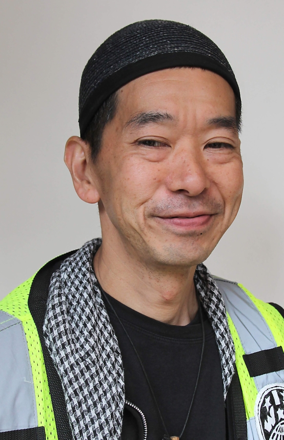 Headshot of Carl Nakajima, Asian man wearing black skullcap and print scarf