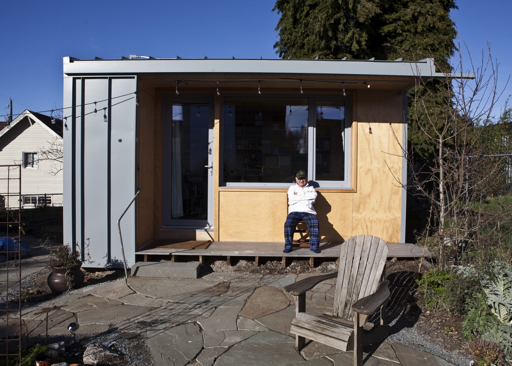 Bobby Desjarlais sits on the porch of his 125-square-foot cottage located in the backyard of a Beacon Hill home. Photo courtesy of Facing Homelessness