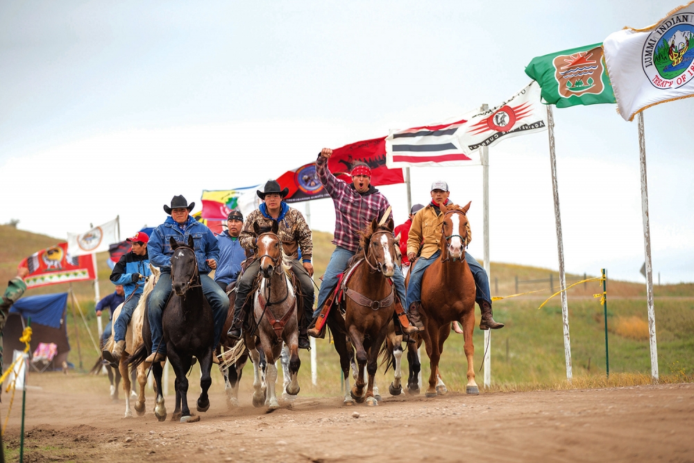 Members of the Cheyenne River Sioux tribe ride along the more than 200  tribal flags that were posted at the protest. Photo by Alex Garland