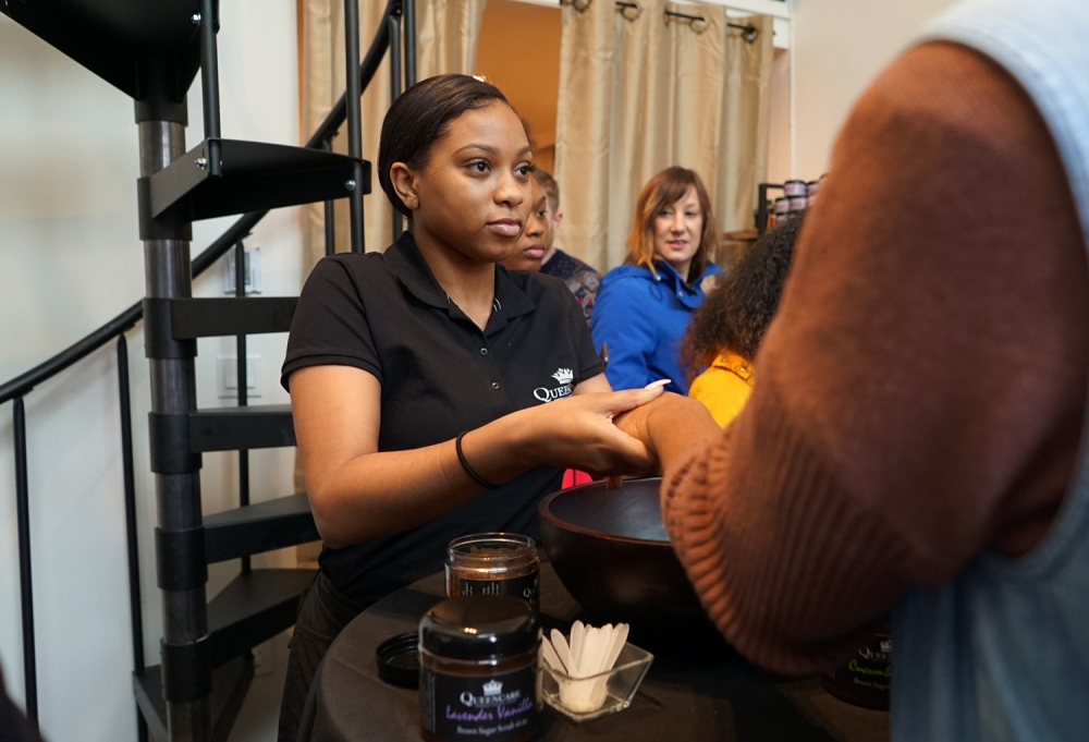 Kiana Green, 17, shows a customer one of the skin care products at QueenCare’s new storefront in  Columbia City. Green is a participant in the Life  Enrichment Group’s Young Queens Youth in Business program. Photo by Susan Fried
