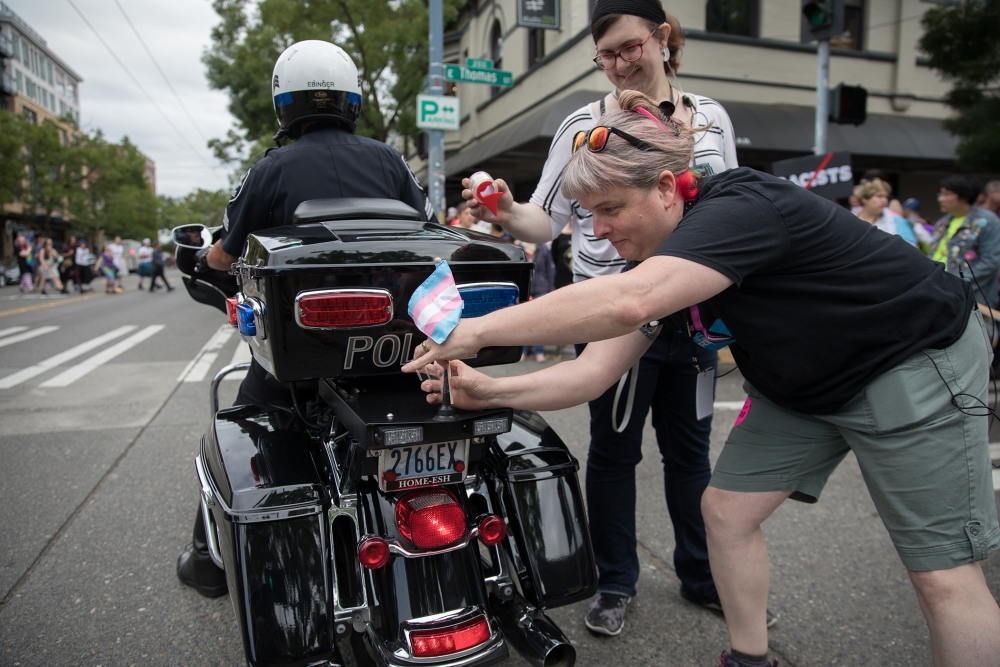 Elayne Wylie, deputy director of the Gender Justice League, attaches a Trans Pride flag to the back of an SPD motorcycle. Photo by Alex Garland