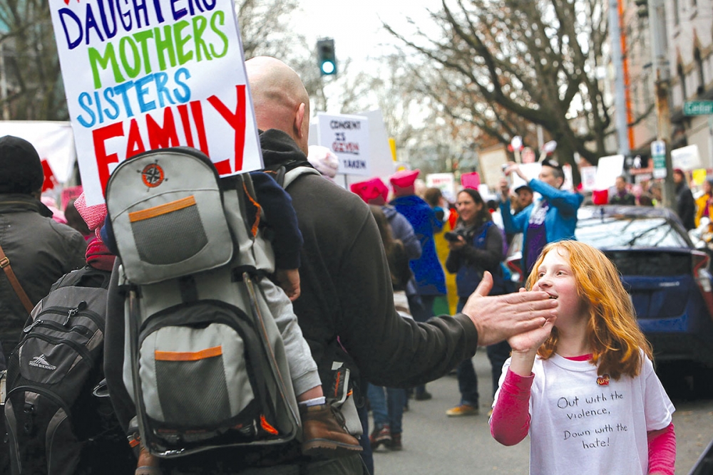 Aleah Nonast hands out high-fives to passing marchers. Photo by Joseph Romain