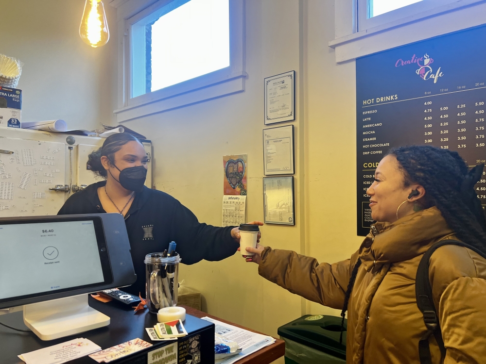 Kash Jones, a barista at Creative Cafe, hands a hot drink to Meagan Crawford, who said the cafe felt “close and intimate.”