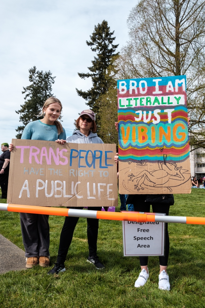 Trans rights activists and supporters hold signs in the designated free speech zone at Olympia, April 6.