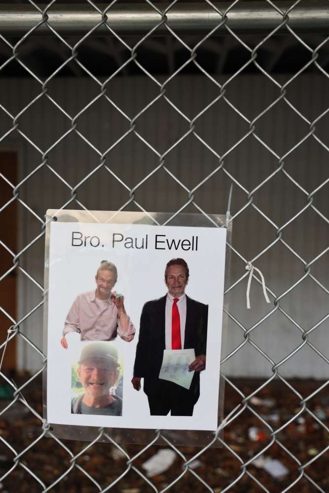 A collage of Paul Ewell is zip tied to a chain link fence among other offerings. 