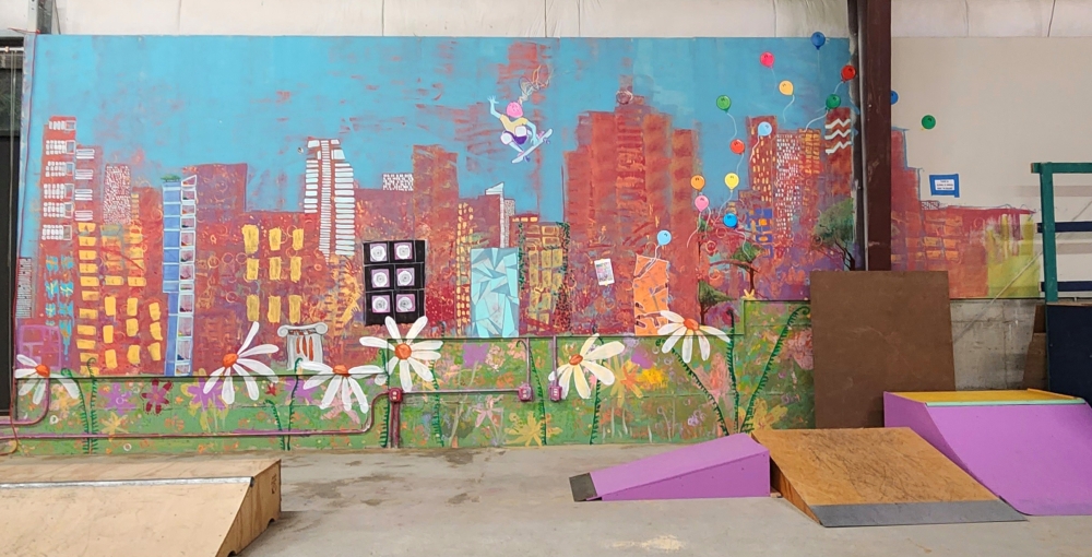A colorful mural on the inside of a warehouse, painted by Skate Like A Girl members and staff