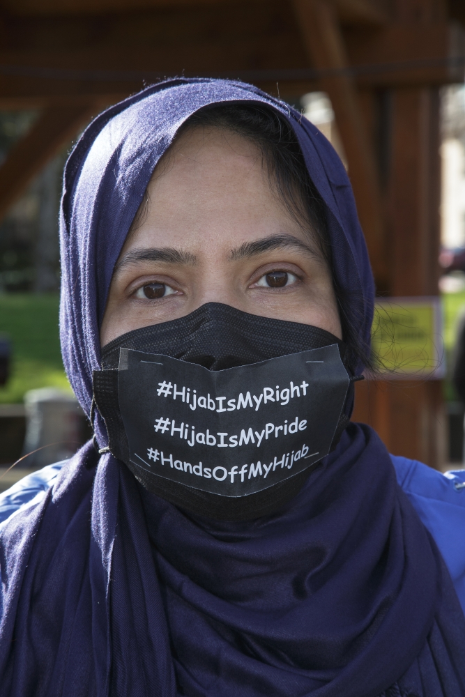 Woman in purple hijab and black face mask with white lettering that reads, "#Hijab Is My Right"
