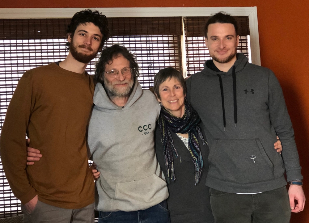 Two tall, dark-haired young men flank a middle-aged couple, man and woman, arms around each other in famiiy photo.