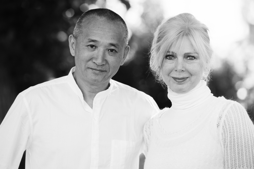 Middle-aged Asian man and white woman, each dressed in white, standing next to each other