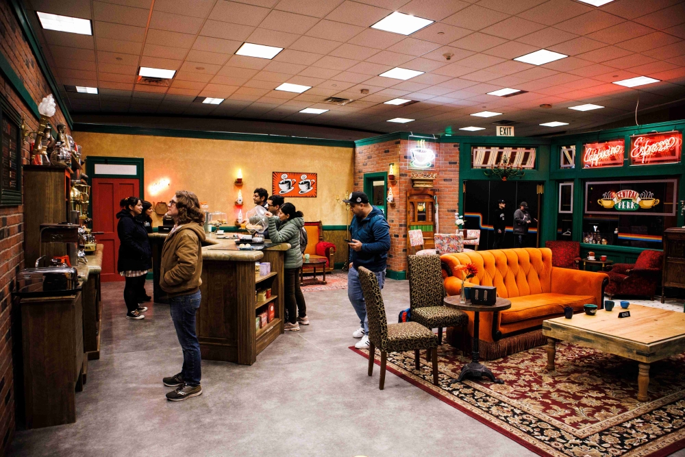 People stand in a space fitted out with "Central Perk" sign and other furniture and memorabilia from "Friends" show.