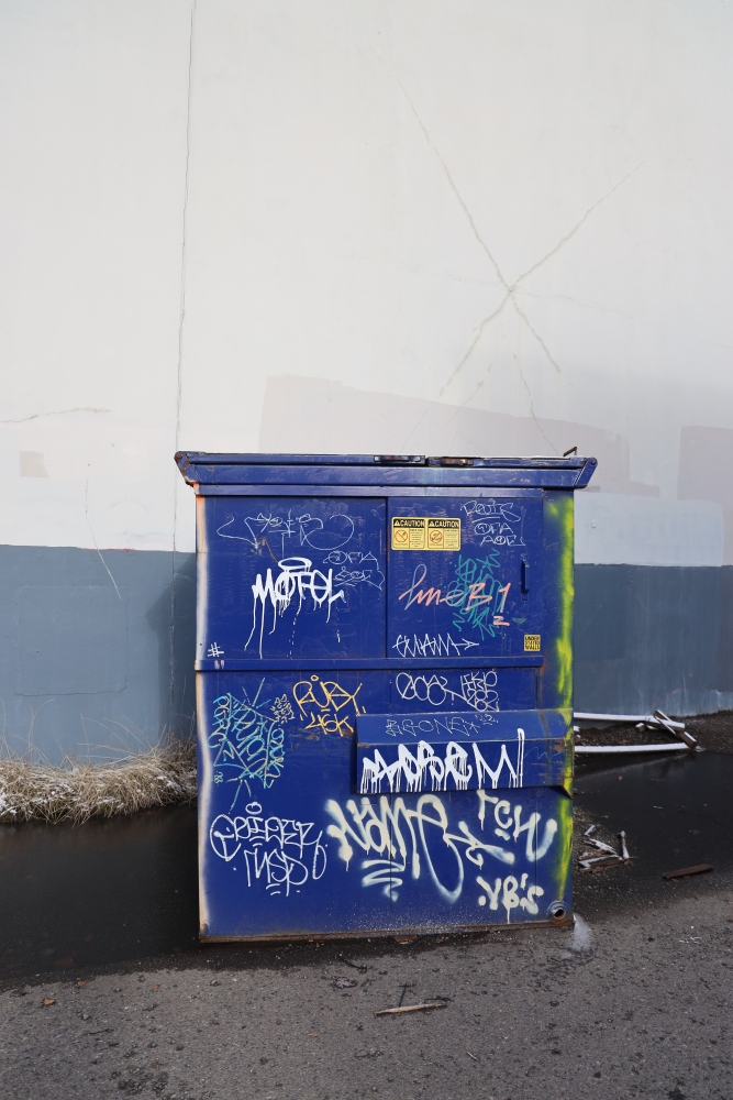 Purple dumpster covered with graffiti tags