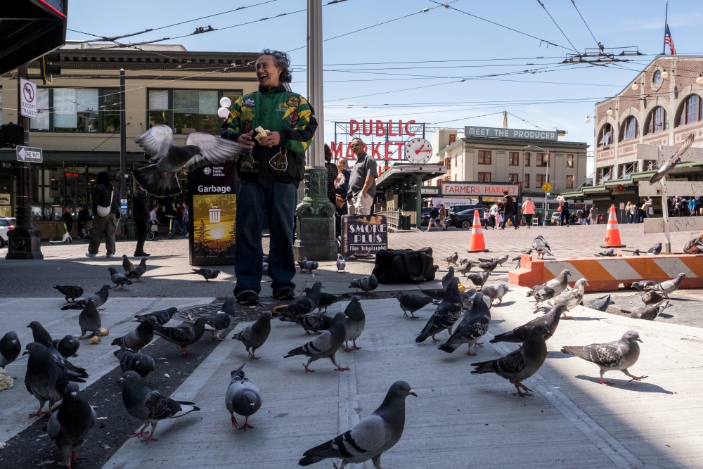 Vendor Willie Jones (badge #9719) finds love and joy by feeding the pigeons near Pike Place Market.